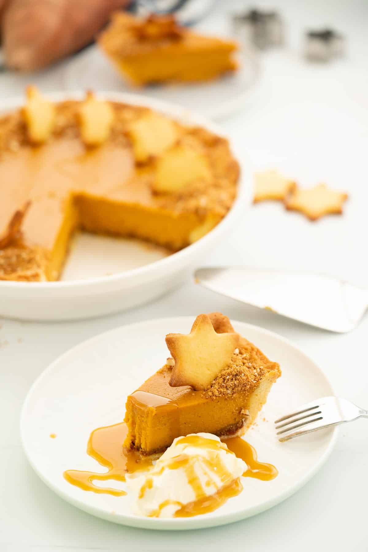 A slice of sweet potato pie decorated with a pastry star, whipped cream and caramel sauce.
