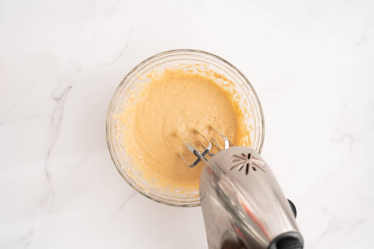 Muffin batter being beaten with a hand held electric beater.