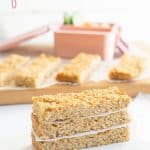 A stack of three oat bars on a white bench top in front of a wooden chopping board with text overlay